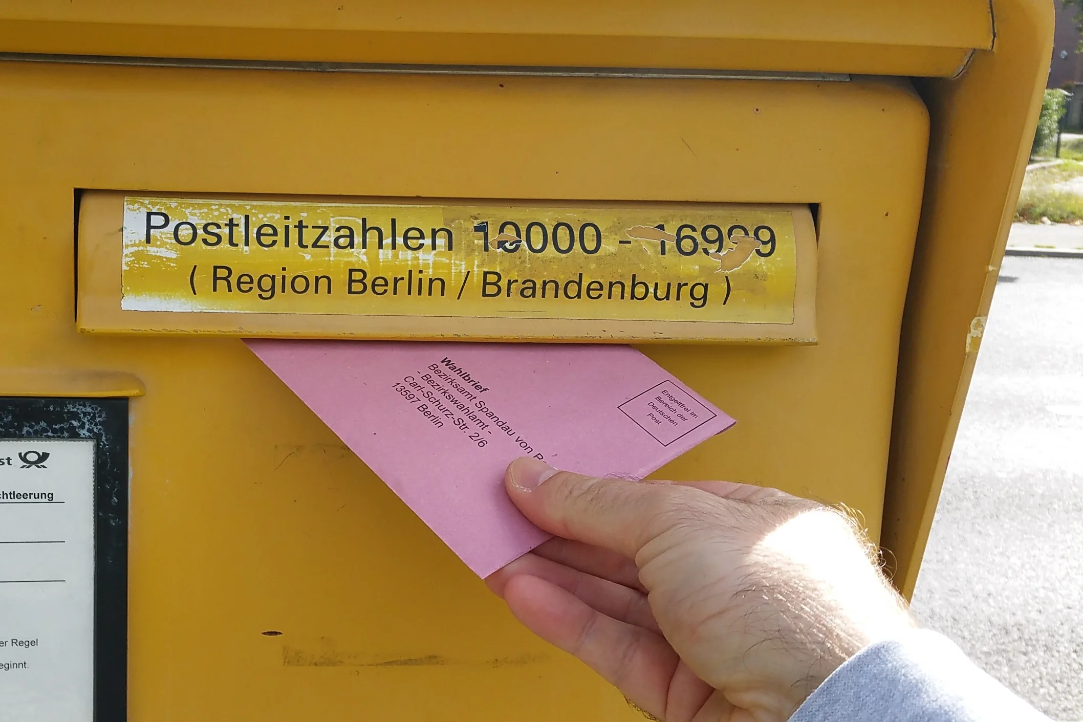 Ein Wahlbrief wird in einen Briefkasten der Deutschen Post eingeworfen